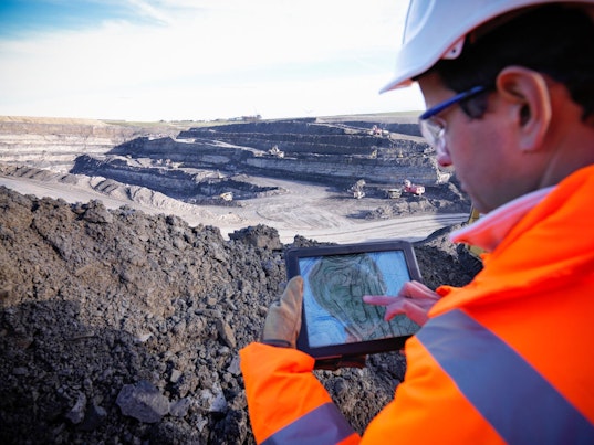 Engineer Using Digital Tablet Surveying Surface Coal Mine