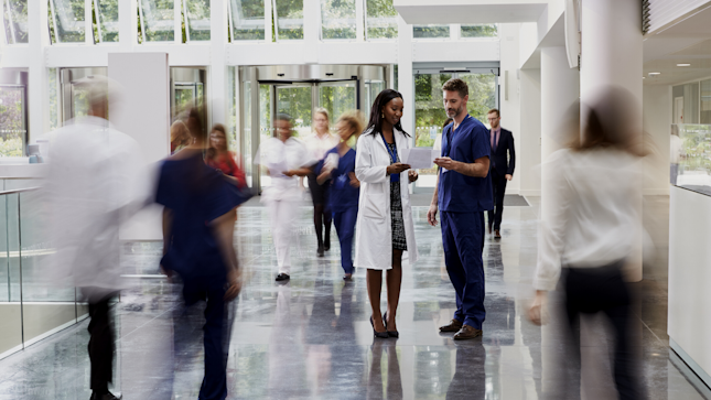 Arzt und Pflegekraft unterhalten sich in der Krankenhauslobby
