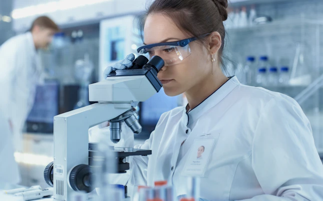 Mujer observando a través de un microscopio en un laboratorio