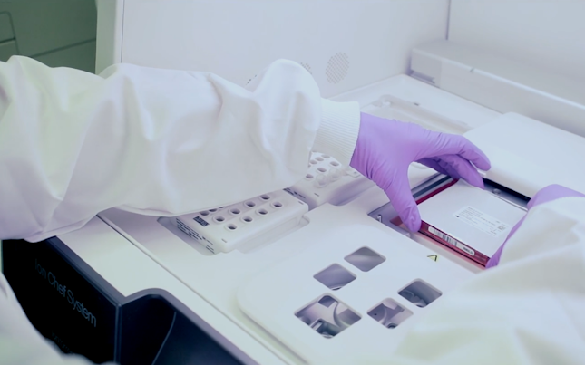 Scientist with violet gloves operating a lab machine
