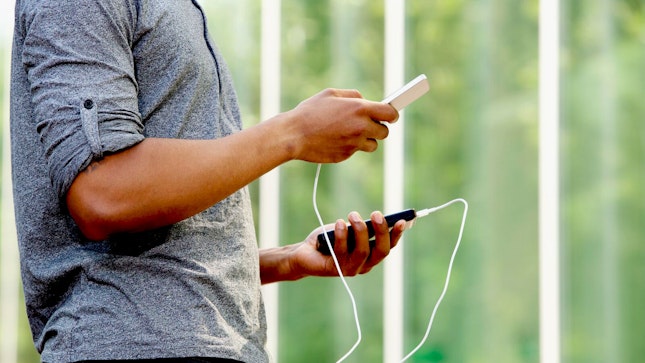 Hombre sosteniendo una batería externa y un smartphone 