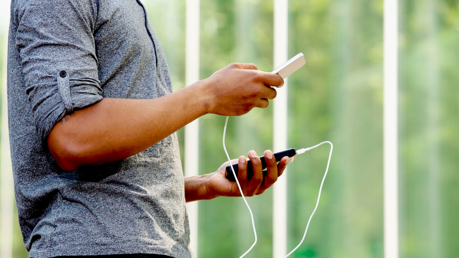 Homme tenant une batterie externe et un smartphone 