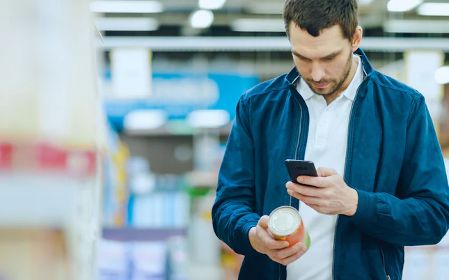 Bărbat ținând în mână o baterie externă și un smartphone