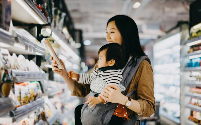 Mother Reading Nutrition Label on Product in a Supermarket