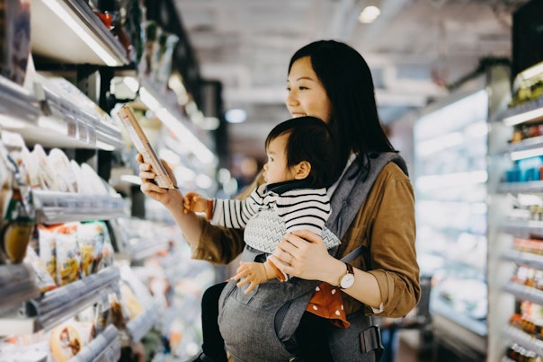 Mother Reading Nutrition Label on Product in a Supermarket