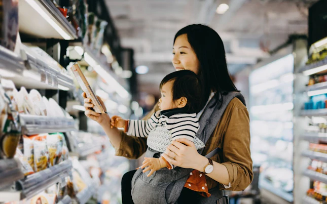 Mother Reading Nutrition Label on Product in a Supermarket