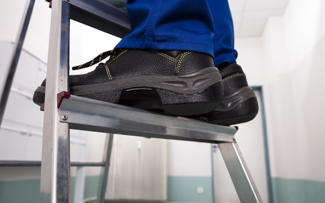 Close up of Safety Shoes Worn by a Man Standing on a Steel Ladder-min