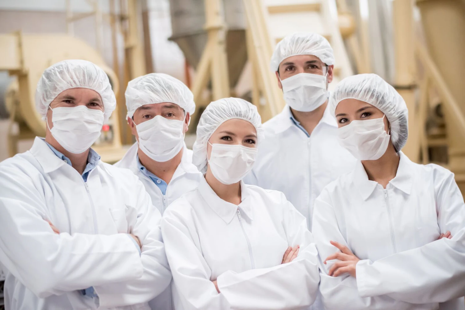Group of Latin American people working at a food factory and wearing uniform