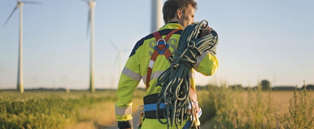Technician Working at Wind Farm Carrying Climbing Equipment