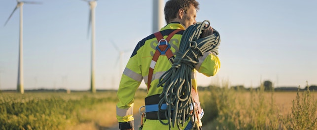 Technician Working at Wind Farm Carrying Climbing Equipment