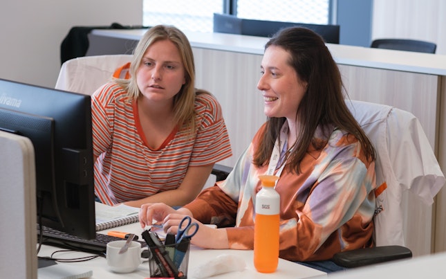 Two Women Looking At Computer In Office