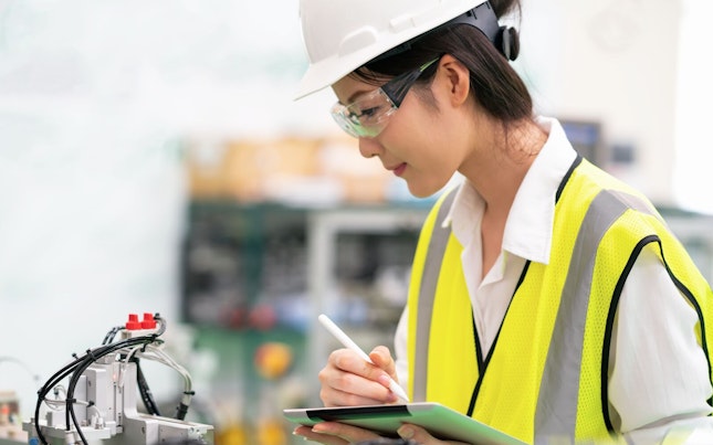 Woman Using Digital Tablet Controlling Machine in a Factory